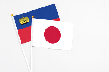 Japan and Liechtenstein stick flags on white background. High quality fabric, miniature national flag. Peaceful global concept.White floor for copy space.