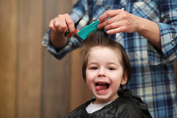 A little boy is trimmed in the hairdresser's bright emotions on face
