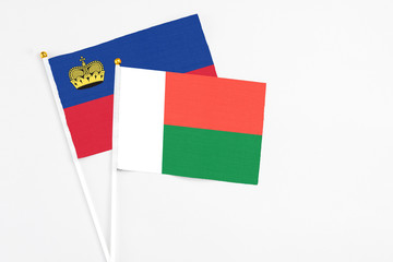 Madagascar and Liechtenstein stick flags on white background. High quality fabric, miniature national flag. Peaceful global concept.White floor for copy space.