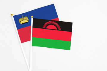Malawi and Liechtenstein stick flags on white background. High quality fabric, miniature national flag. Peaceful global concept.White floor for copy space.