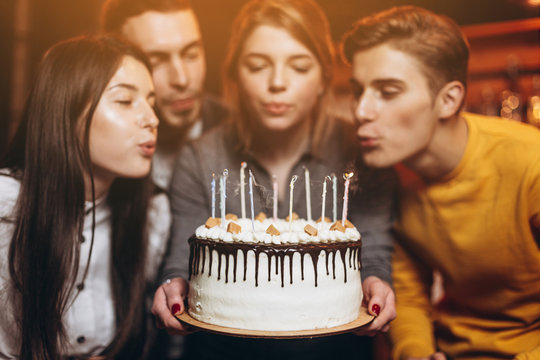 A Charming Woman Blows Out Candles On A Cake After Making A Wish On Her Birthday. The Company Of Best Friends Came To Congratulate The Girlfriend On Holiday