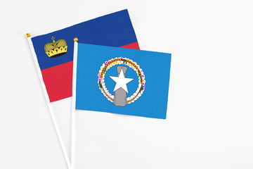 Northern Mariana Islands and Liechtenstein stick flags on white background. High quality fabric, miniature national flag. Peaceful global concept.White floor for copy space.