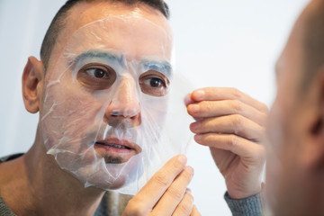 man applying a facial mask to himself.