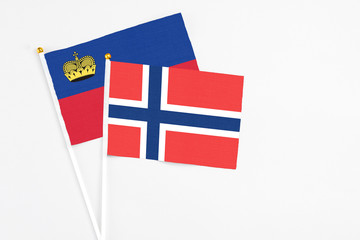 Obraz premium Norway and Liechtenstein stick flags on white background. High quality fabric, miniature national flag. Peaceful global concept.White floor for copy space.