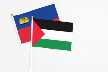 Palestine and Liechtenstein stick flags on white background. High quality fabric, miniature national flag. Peaceful global concept.White floor for copy space.