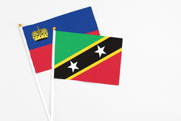 Obraz premium Saint Kitts And Nevis and Liechtenstein stick flags on white background. High quality fabric, miniature national flag. Peaceful global concept.White floor for copy space.