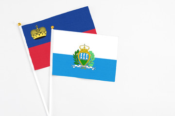 San Marino and Liechtenstein stick flags on white background. High quality fabric, miniature national flag. Peaceful global concept.White floor for copy space.
