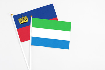 Sierra Leone and Liechtenstein stick flags on white background. High quality fabric, miniature national flag. Peaceful global concept.White floor for copy space.