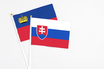 Slovakia and Liechtenstein stick flags on white background. High quality fabric, miniature national flag. Peaceful global concept.White floor for copy space.