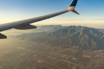 The sun sets as an airplane soars above the mountains and countryside outside Los Angeles.