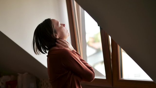 Depressed woman standing by the loft window felling sad