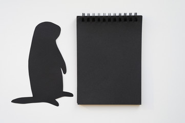 Groundhog day. Groundhog silhouette cut from black paper and black blank notebook on white background. Space for text