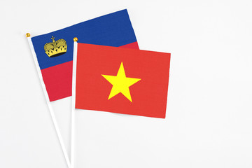 Vietnam and Liechtenstein stick flags on white background. High quality fabric, miniature national flag. Peaceful global concept.White floor for copy space.