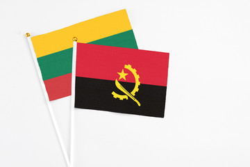 Angola and Lithuania stick flags on white background. High quality fabric, miniature national flag. Peaceful global concept.White floor for copy space.