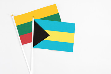Bahamas and Lithuania stick flags on white background. High quality fabric, miniature national flag. Peaceful global concept.White floor for copy space.
