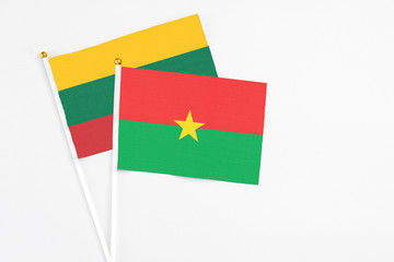Burkina Faso and Lithuania stick flags on white background. High quality fabric, miniature national flag. Peaceful global concept.White floor for copy space.