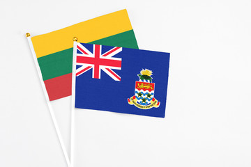 Fototapeta premium Cayman Islands and Lithuania stick flags on white background. High quality fabric, miniature national flag. Peaceful global concept.White floor for copy space.
