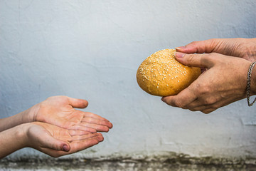 Hands of a child take a bun from the hands of an adult. Peace. Sadness