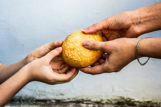 Hands of a child take a bun from the hands of an adult. Peace. Sadness