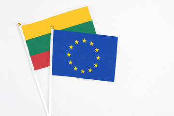 European Union and Lithuania stick flags on white background. High quality fabric, miniature national flag. Peaceful global concept.White floor for copy space.