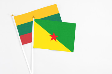 French Guiana and Lithuania stick flags on white background. High quality fabric, miniature national flag. Peaceful global concept.White floor for copy space.