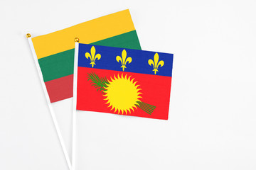 Guadeloupe and Lithuania stick flags on white background. High quality fabric, miniature national flag. Peaceful global concept.White floor for copy space.