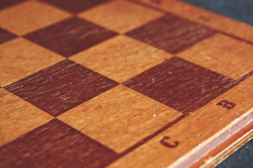    Background with vintage wooden chessboard on dark textured table. Selective focus, copy space.    