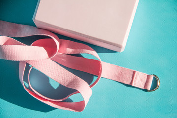 Yoga accessories. A pink cube and yoga strap lie on a blue rug.