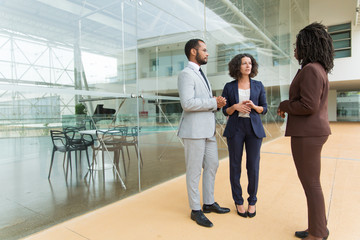 Interracial business team discussing project near office building. Business man and women standing...