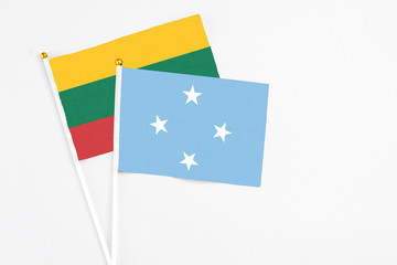 Micronesia and Lithuania stick flags on white background. High quality fabric, miniature national flag. Peaceful global concept.White floor for copy space.