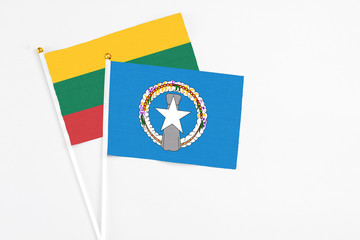 Northern Mariana Islands and Lithuania stick flags on white background. High quality fabric, miniature national flag. Peaceful global concept.White floor for copy space.