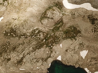 vue aérienne de haute montagne en altitude avec chemin de randonnée et neiges éternelles décors rocheux sec avec peu de végétation