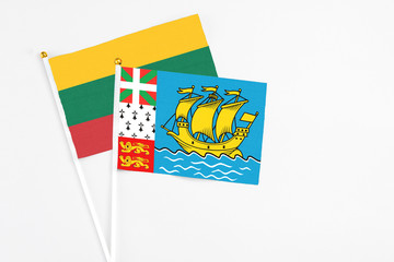 Saint Pierre And Miquelon and Lithuania stick flags on white background. High quality fabric, miniature national flag. Peaceful global concept.White floor for copy space.