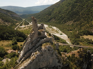 vue aérienne d'une tour en ruine sur un piton rocheux escarpé dans une vallée de montagne bien...