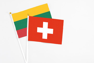 Switzerland and Lithuania stick flags on white background. High quality fabric, miniature national flag. Peaceful global concept.White floor for copy space.
