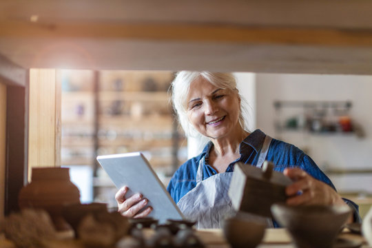 Senior craftswoman with tablet computer in art studio