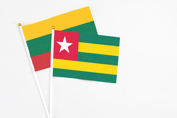 Togo and Lithuania stick flags on white background. High quality fabric, miniature national flag. Peaceful global concept.White floor for copy space.