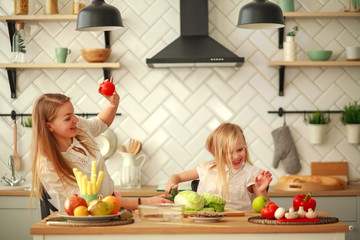 Joyful mother with daughter at home in kitchen having fun playing with food