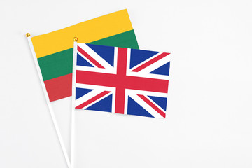 Fototapeta premium United Kingdom and Lithuania stick flags on white background. High quality fabric, miniature national flag. Peaceful global concept.White floor for copy space.
