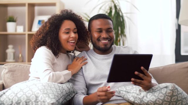 family, technology, communication and people concept - smiling happy african american couple with tablet pc computer having video call at home