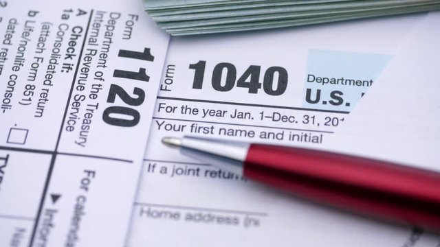 USA tax form 1040, 1120, and dollar bills, close up