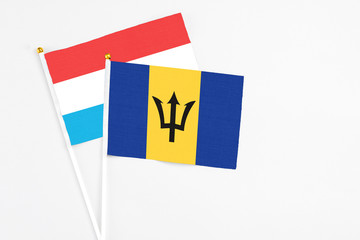 Barbados and Luxembourg stick flags on white background. High quality fabric, miniature national flag. Peaceful global concept.White floor for copy space.