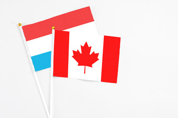 Canada and Luxembourg stick flags on white background. High quality fabric, miniature national flag. Peaceful global concept.White floor for copy space.