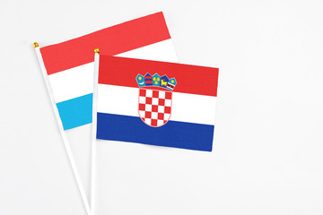 Croatia and Luxembourg stick flags on white background. High quality fabric, miniature national flag. Peaceful global concept.White floor for copy space.