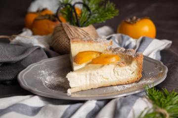 cheesecake and persimmons, dark gray background. rustic breakfast concept.
