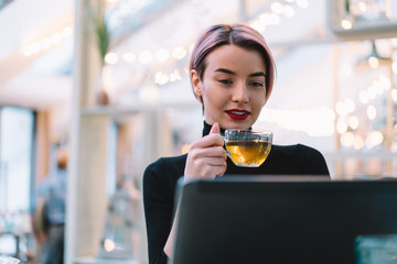 Cheerful woman using tablet in cafeteria