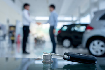 Agreements to buy new cars, new car loans or signing contracts with car keys and money in the foreground Blurred background for two business people standing hand in hand