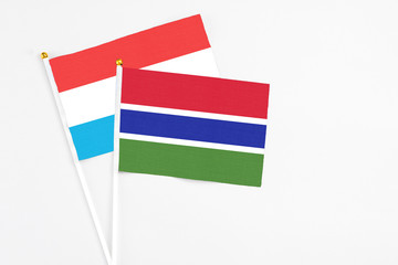 Gambia and Luxembourg stick flags on white background. High quality fabric, miniature national flag. Peaceful global concept.White floor for copy space.