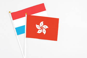 Hong Kong and Luxembourg stick flags on white background. High quality fabric, miniature national flag. Peaceful global concept.White floor for copy space.