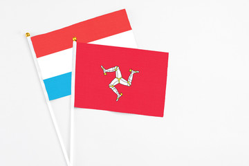 Isle Of Man and Luxembourg stick flags on white background. High quality fabric, miniature national flag. Peaceful global concept.White floor for copy space.